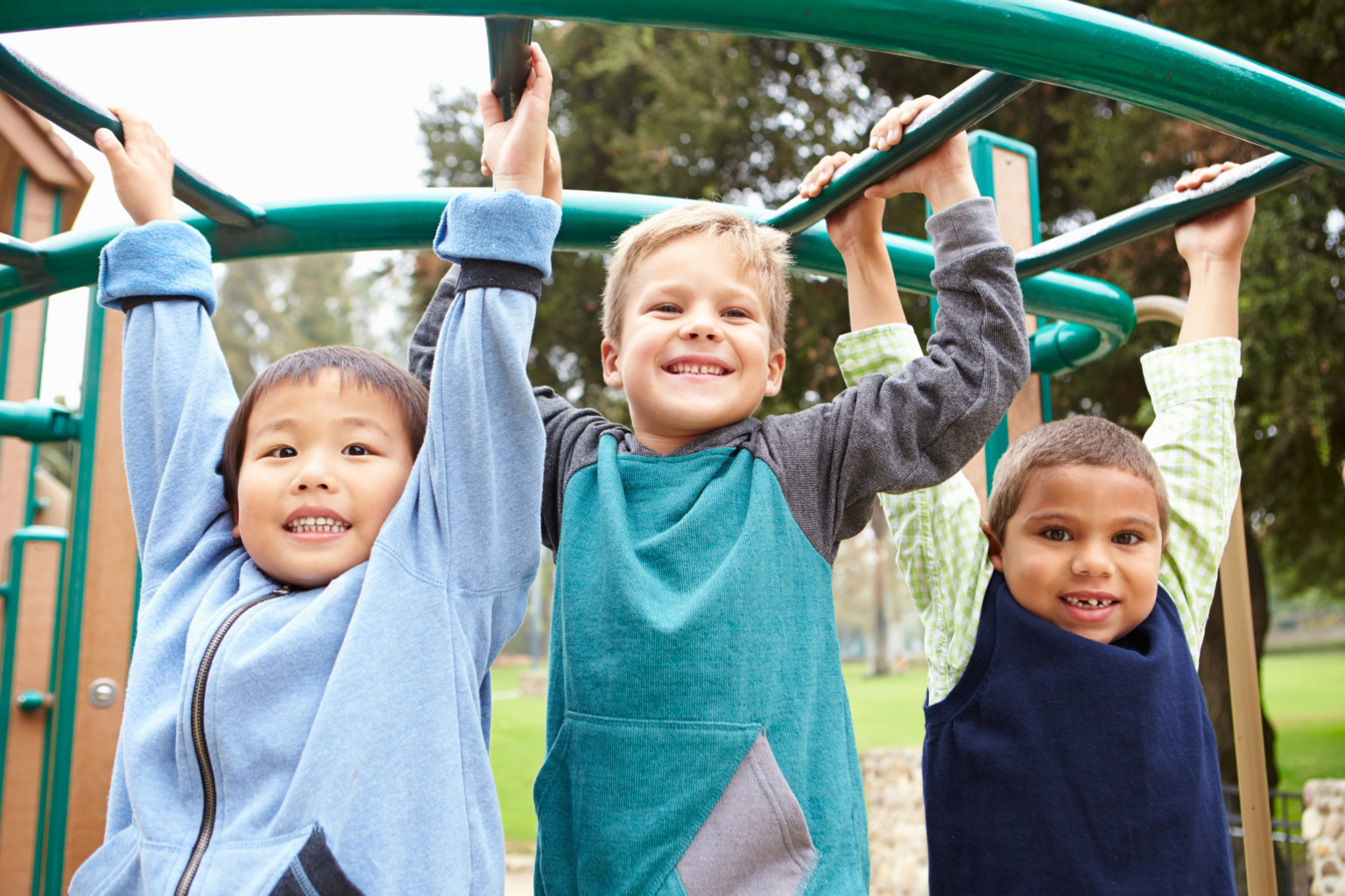 Three Young Boys On Climbing Frame In Playground