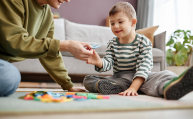 Happy Little Boy With Down Syndrome Playing With Letters On Floor